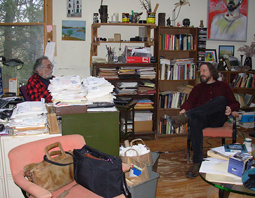 A photo of Robert Schoch and John Anthony West sitting and speaking with other 
					in JAW's home in New York